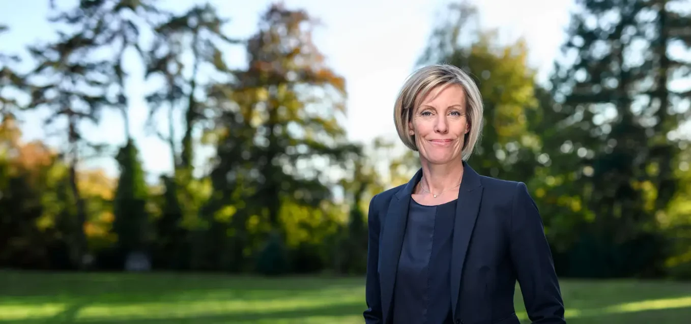 Anna Dunand, Chief Business Development Officer, standing on the IMD Lausanne campus gardens