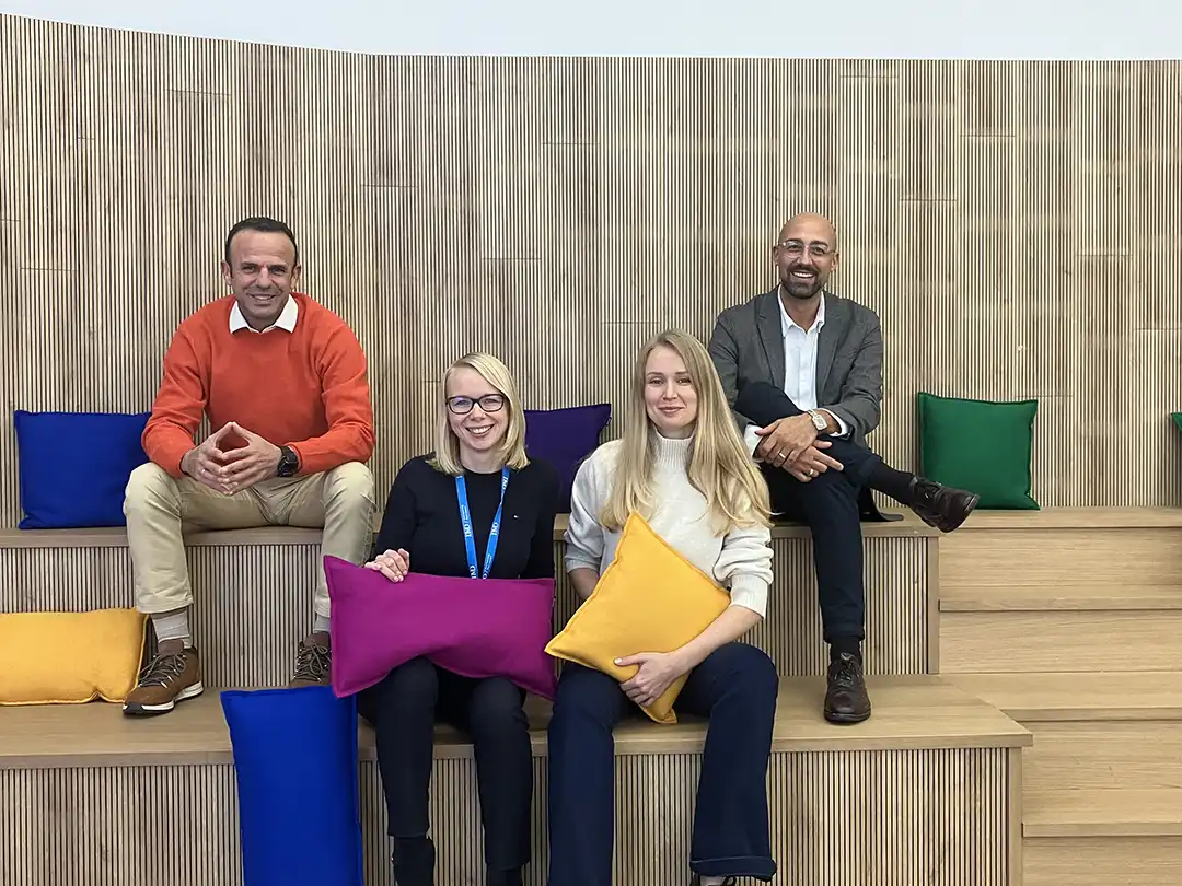 IMD MBA career development team photo inside the campus sitting on a bench together, the image consists of 2 women and 2 men.